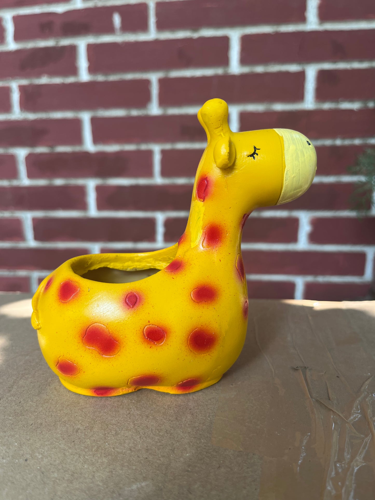 Playful giraffe-shaped planter with a bright yellow design and red spots, ideal for holding succulents or small indoor plants. This unique planter adds a fun and whimsical element to any home decor. Explore more decorative succulent pots like this at Plant Orbit.