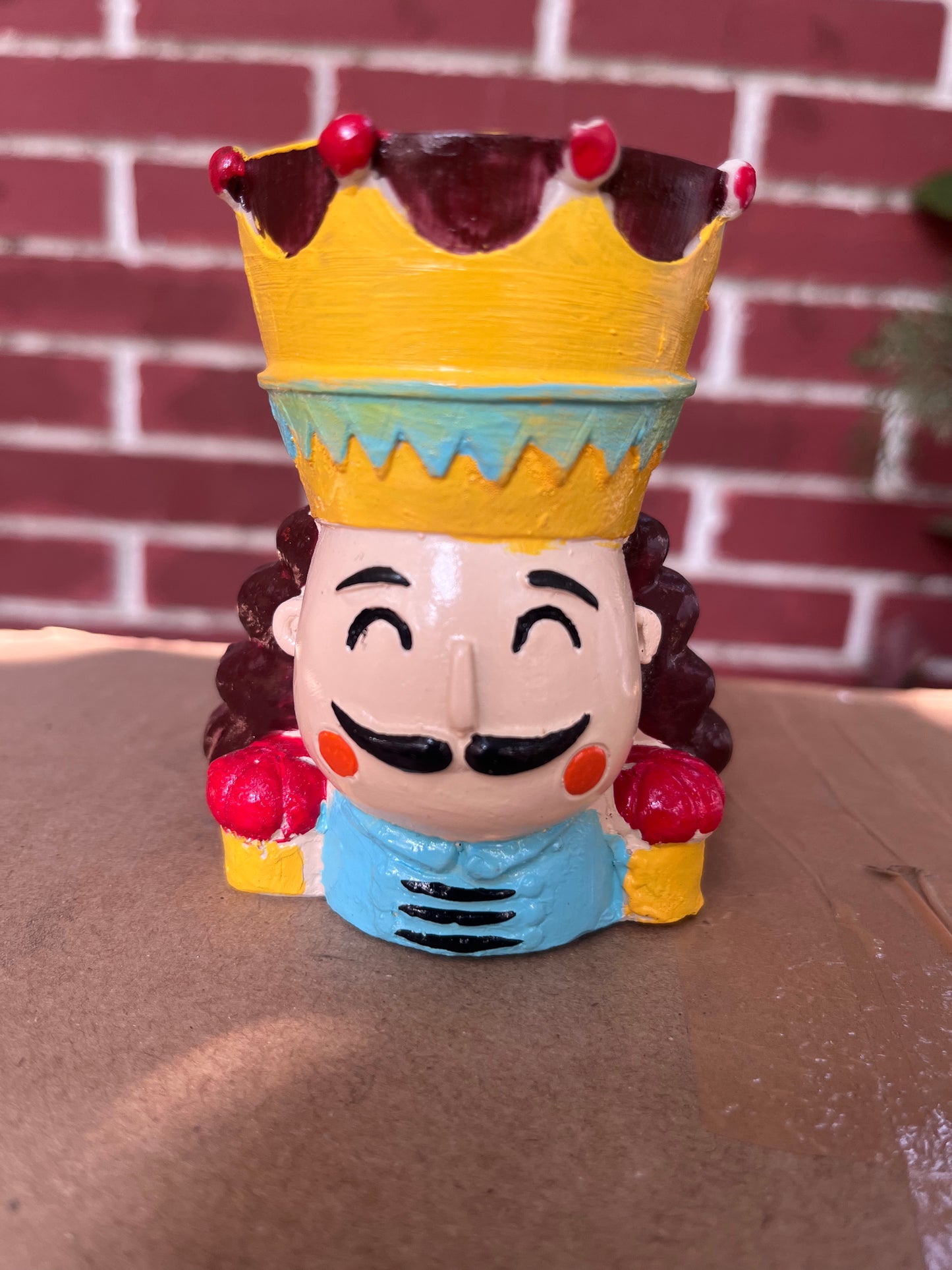 Whimsical king-shaped planter featuring a colorful crown and cheerful expression, perfect for holding succulents or small indoor plants. This unique planter adds a regal touch and fun character to any indoor space. Find more decorative succulent pots like this at Plant Orbit.